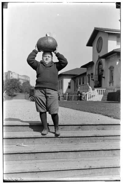 Exhibit.
Children's Garden, 1925.
Boy on wooden steps.  Mammoth pumpkin on head.